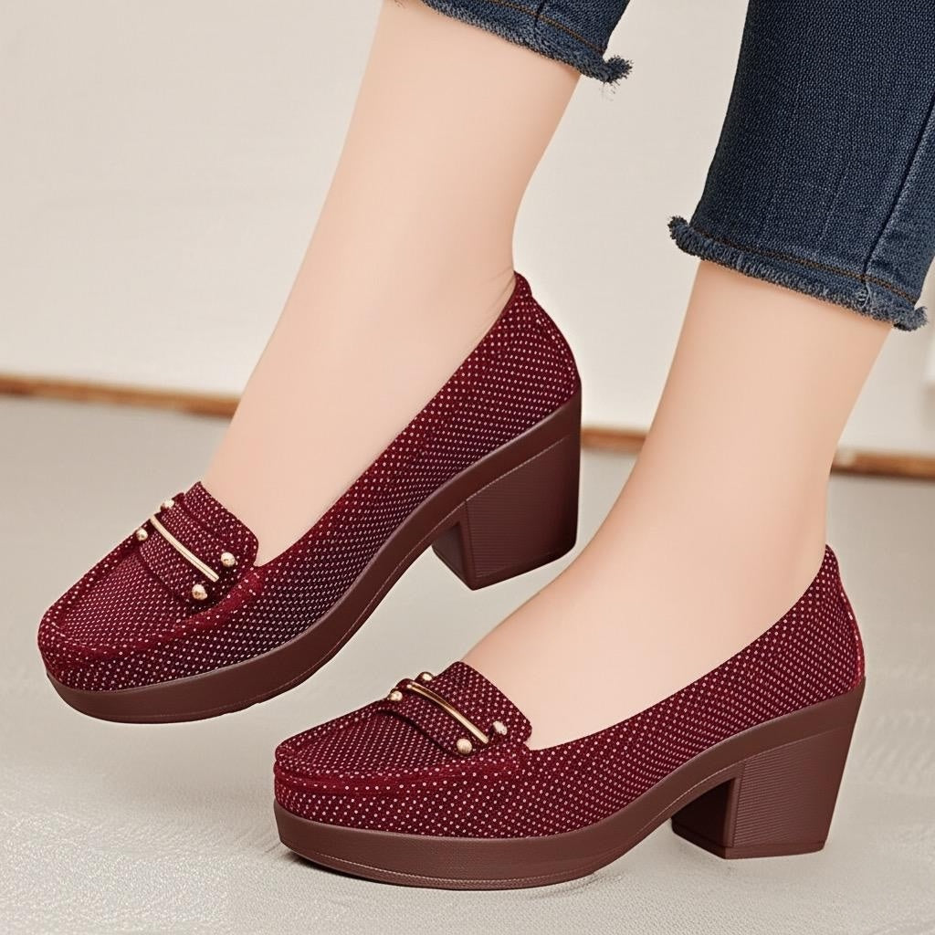 Red platform shoes with gold buckles worn by a person in jeans.