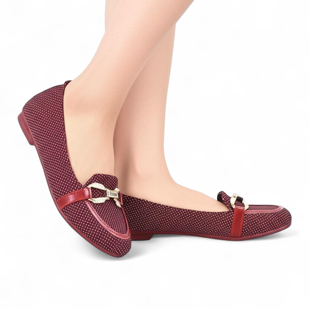 Red polka dot shoes with a strap worn by a person on a white background