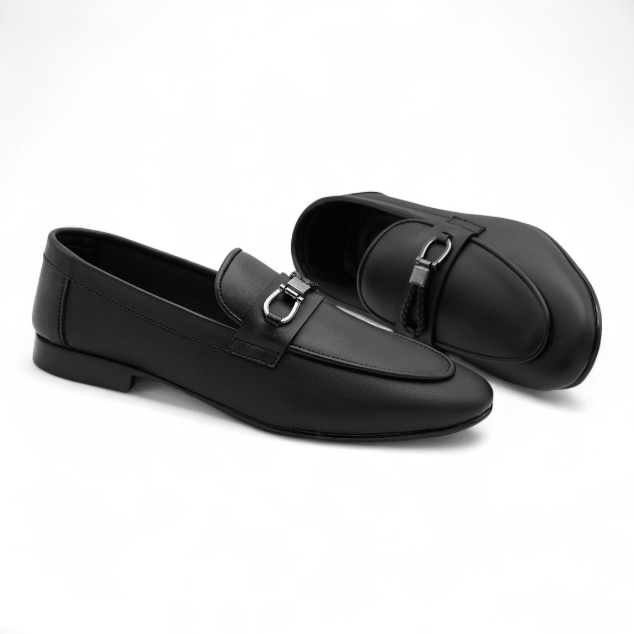 Pair of black loafers with a silver buckle on a white background