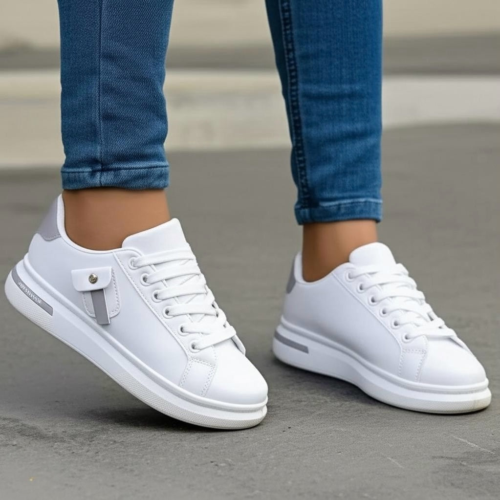 White sneakers worn with blue jeans on a neutral background