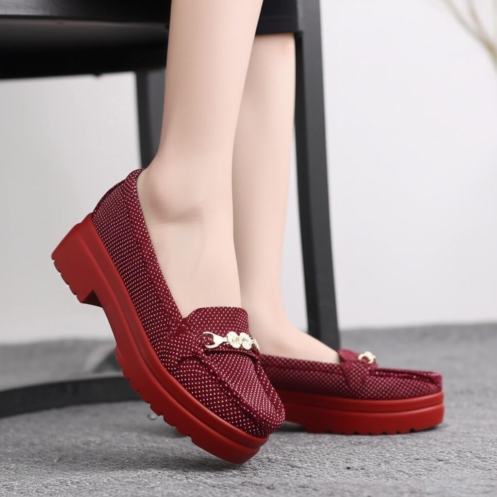 Red loafers worn by a person on a neutral background