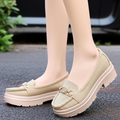 Beige loafers worn on feet with a blurred background