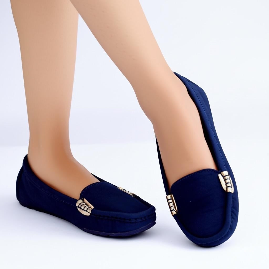 Navy blue loafers with gold accents worn by a person on a white background