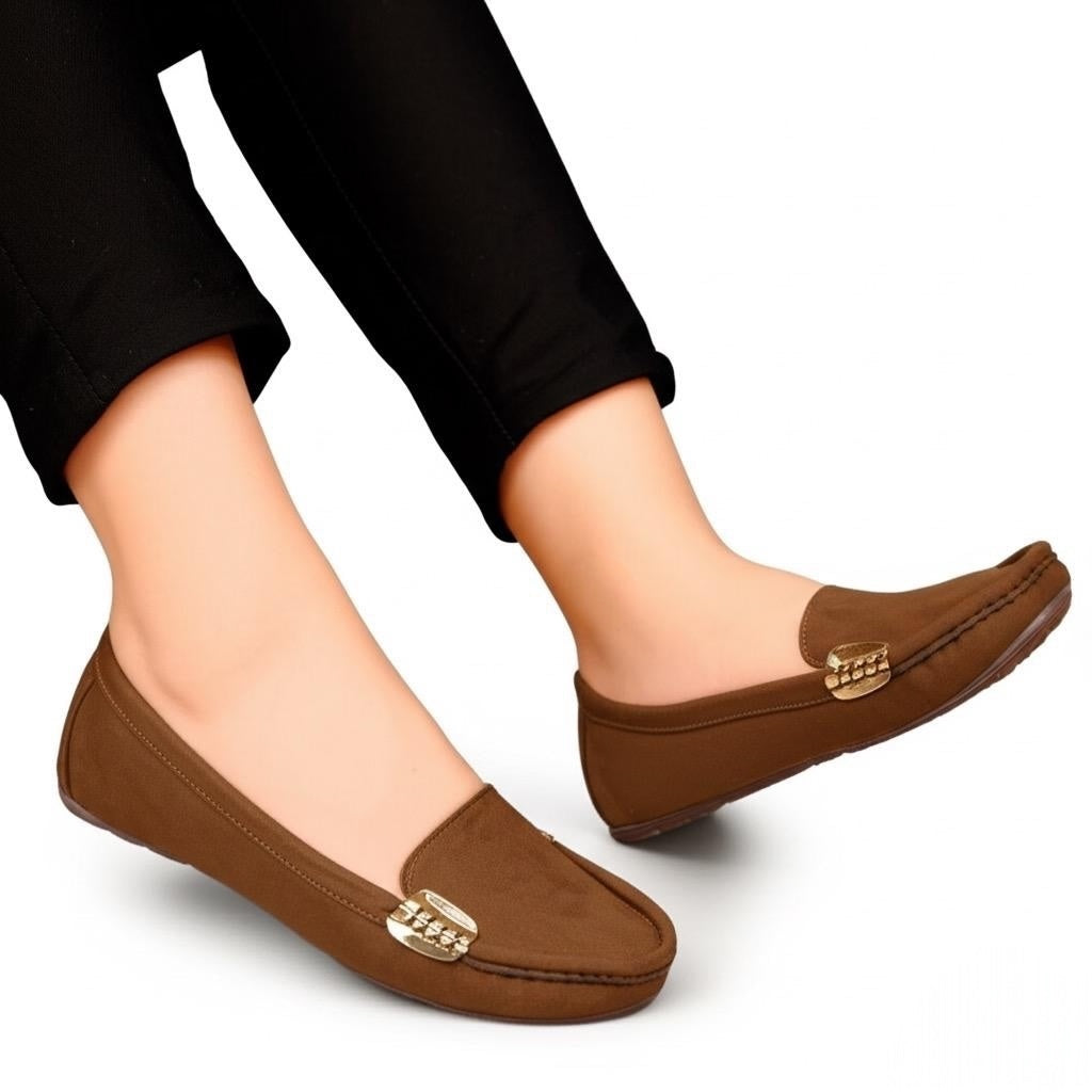 Brown loafers with gold accents worn by a person on a white background