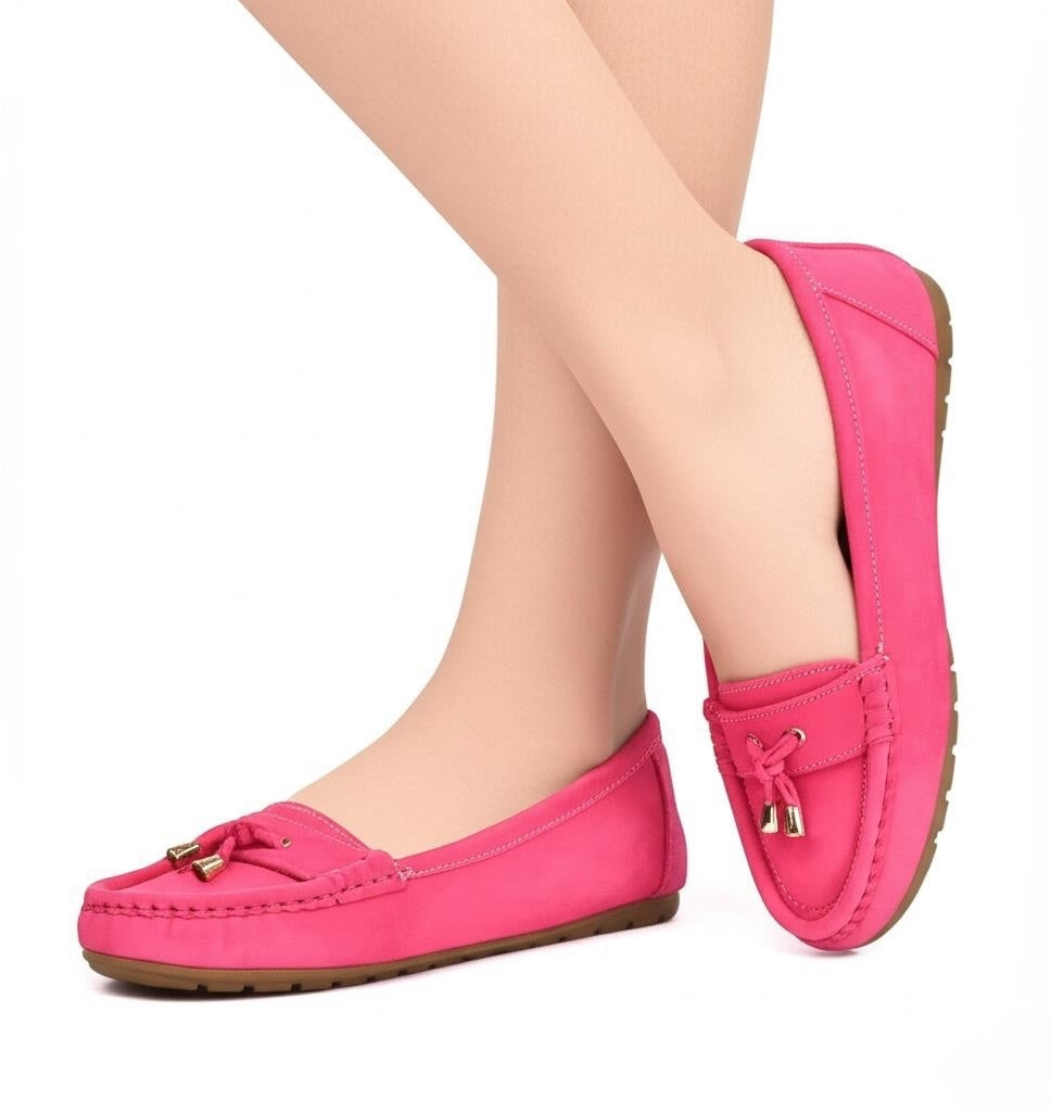 Pink loafers worn by a person on a white background