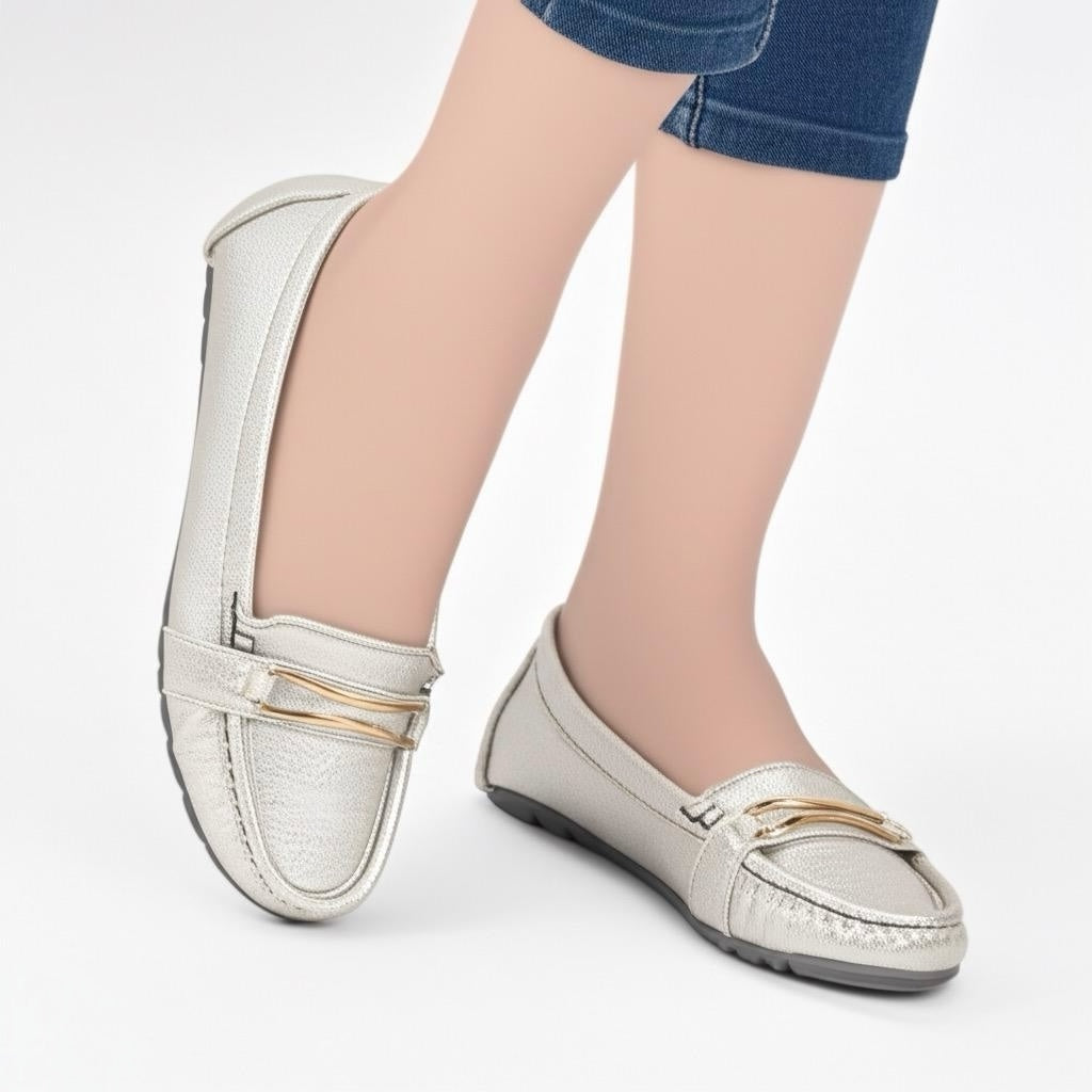 White loafers with gold accents worn by a person on a white background