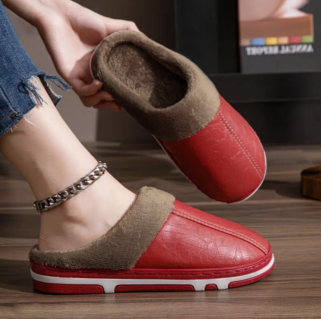 A person wearing red and brown faux leather half shoes with a warm fur lining.