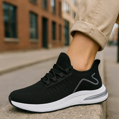 Black running shoe with white sole worn by a person on a city street.