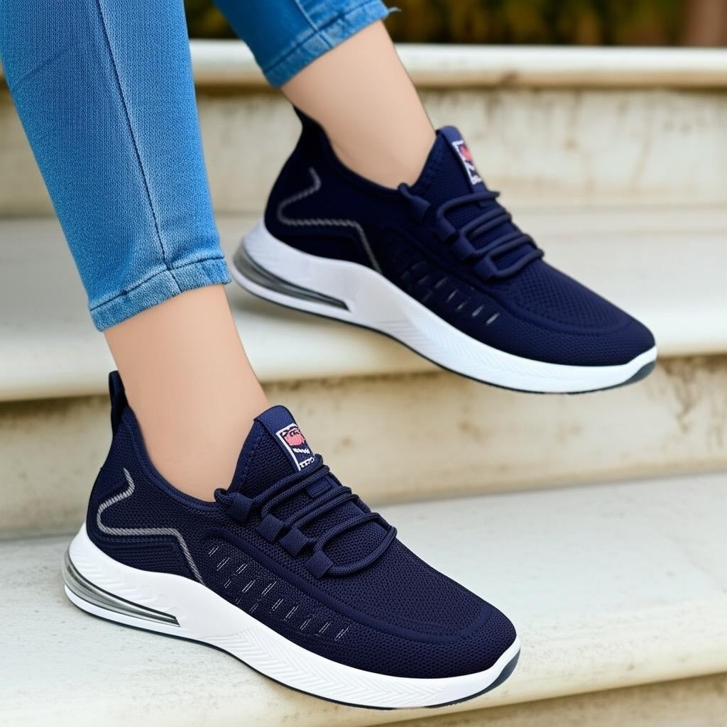 Navy blue running shoes with white soles worn by a person on steps.