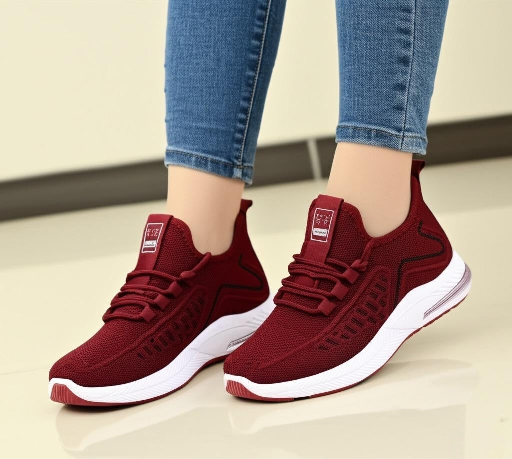 Red sneakers with white soles worn with blue jeans on a light background